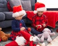 Adorable boy and girl celebrating christmas holding candies and decoration ball at home