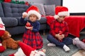 Adorable boy and girl celebrating christmas holding candies and decoration ball at home
