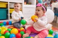 Adorable boy and girl playing with balls sitting on floor at kindergarten Royalty Free Stock Photo