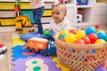 Adorable boy and girl playing with balls sitting on floor at kindergarten Royalty Free Stock Photo