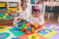 Adorable boy and girl playing with balls sitting on floor at kindergarten Royalty Free Stock Photo