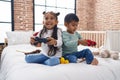 Adorable boy and girl playing video game sitting on sofa at bedroom Royalty Free Stock Photo