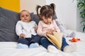 Adorable boy and girl reading book sitting on bed at bedroom Royalty Free Stock Photo