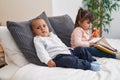 Adorable boy and girl reading book sitting on bed at bedroom Royalty Free Stock Photo