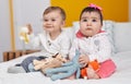 Adorable boy and girl sitting on bed playing with toys at bedroom Royalty Free Stock Photo