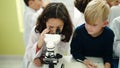 Adorable boy and girl students using microscope writing notes at laboratory classroom Royalty Free Stock Photo