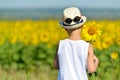 Adorable boy in hat holding sunflower behind his back on yellow field blue sky outdoors Royalty Free Stock Photo