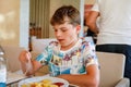 Adorable boy having breakfast at resort restaurant. Happy school kid child eating healthy food, vegetables and eggs in Royalty Free Stock Photo