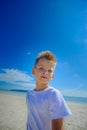 Adorable boy having fun on the tropical beach. White t-shirt, dark trousers and sunglasses. Barefoot on white sand. Royalty Free Stock Photo