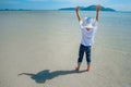 Adorable boy having fun on the tropical beach. White t-shirt, dark trousers and sunglasses. Barefoot on white sand. Royalty Free Stock Photo