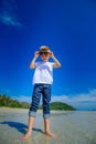 Adorable boy having fun on the tropical beach. White t-shirt, dark trousers and sunglasses. Barefoot on white sand. Royalty Free Stock Photo