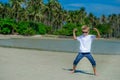 Adorable boy having fun on the tropical beach. White t-shirt, dark trousers and sunglasses. Barefoot on white sand. Royalty Free Stock Photo