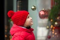 Adorable boy kid looking through the display window at Christmas decoration in the shop Royalty Free Stock Photo