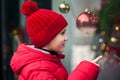 Adorable boy kid looking through the display window at Christmas decoration in the shop Royalty Free Stock Photo
