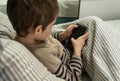 Adorable boy playing game with a smart phone. Danger of internet.