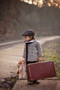 Adorable boy on a railway station, waiting for the train with suitcase and teddy bear Royalty Free Stock Photo