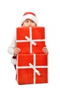Adorable boy in santa clothes peeks out behind Christmas big gift boxs. Isolated white background. Royalty Free Stock Photo