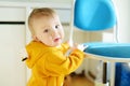 Adorable boy standing by the chair on bright living room. Toddler learning how to stand up unassisted Royalty Free Stock Photo