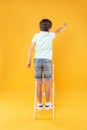 Adorable boy standing on the ladder