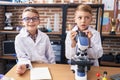 Adorable boys students using microscope writing notes at laboratory classroom Royalty Free Stock Photo