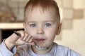 Adorable caucasian baby boy with blue eyes and blond ginger hair eating porridge by himself. Royalty Free Stock Photo