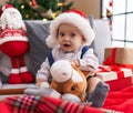 Adorable caucasian baby holding horse toy sitting on sofa by christmas tree at home Royalty Free Stock Photo