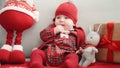 Adorable caucasian baby sitting on sofa with santa claus toy and christmas gift at home Royalty Free Stock Photo