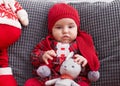 Adorable caucasian baby sitting on sofa with santa claus toy at home Royalty Free Stock Photo