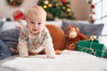 Adorable caucasian baby smiling confident crawling on sofa by christmas tree at home Royalty Free Stock Photo