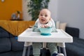 Adorable caucasian baby smiling confident sitting on highchair at home Royalty Free Stock Photo