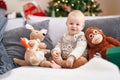 Adorable caucasian baby smiling confident sitting on sofa by christmas tree at home Royalty Free Stock Photo