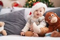 Adorable caucasian baby smiling confident sitting on sofa by christmas tree at home Royalty Free Stock Photo