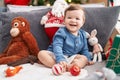 Adorable caucasian baby smiling confident sitting on sofa by christmas tree at home Royalty Free Stock Photo