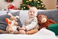 Adorable caucasian baby smiling confident sitting on sofa by christmas tree at home Royalty Free Stock Photo