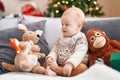 Adorable caucasian baby smiling confident sitting on sofa by christmas tree at home Royalty Free Stock Photo