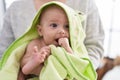 Adorable caucasian baby sucking hand wearing frog towel on mother arms at home Royalty Free Stock Photo