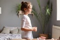 Adorable caucasian child lovely little girl with dark hair and bun hairstyle smiling looking ahead standing in her cozy light Royalty Free Stock Photo