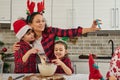 Adorable Caucasian children kneading dough, helping their mother in cooking Christmas bread and cookies. Delighted mom recording Royalty Free Stock Photo