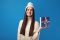 Girl wearing white oversize sweater and hat, holding present box for christmas Royalty Free Stock Photo