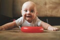 Adorable caucasian infant boy smiling lying on sofa with developing toy. Early baby development concept. Royalty Free Stock Photo