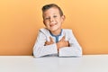 Adorable caucasian kid wearing casual clothes sitting on the table happy face smiling with crossed arms looking at the camera Royalty Free Stock Photo