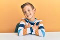 Adorable caucasian kid wearing casual clothes sitting on the table happy face smiling with crossed arms looking at the camera Royalty Free Stock Photo