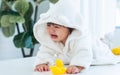 Adorable caucasian little baby daughter girl, wearing cute white bathrobe, taking bath in morning, sitting in baby bathtub, crying Royalty Free Stock Photo