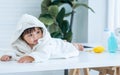 Adorable caucasian little baby daughter girl, wearing cute white bathrobe, taking bath in morning, sitting in baby bathtub, Royalty Free Stock Photo