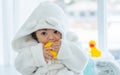 Adorable caucasian little baby daughter girl, wearing cute white bathrobe, taking bath in morning, sitting in baby bathtub, Royalty Free Stock Photo