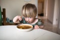 Adorable caucasian toddler boy eating healthy soup in the kitch Royalty Free Stock Photo