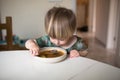 Adorable caucasian toddler boy eating healthy soup in the kitch Royalty Free Stock Photo