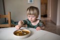 Adorable caucasian toddler boy eating healthy soup in the kitch Royalty Free Stock Photo