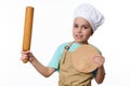 Adorable child boy, in chef's hat and apron, posing with a rolling pin and wooden cutting board, over white
