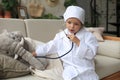 Adorable child dressed as doctor playing with toy elephant, checking its breath with stethoscope Royalty Free Stock Photo